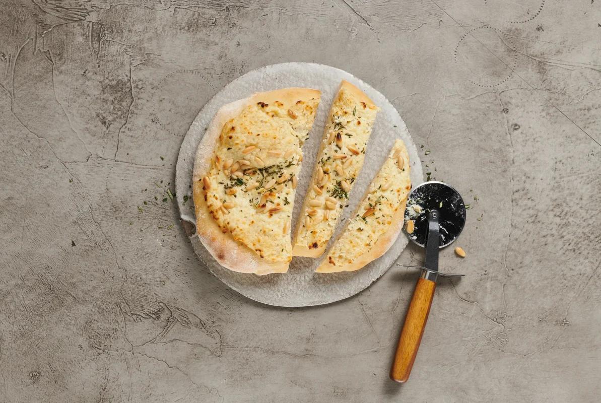 Pizza bianca aus der Kategorie Gebäck salzig. Das fertige Gericht schön angerichtet und fotografiert aus Vogelperspektive (Food Fotografie). Serviervorschlag, Original Tiptopf Rezept, aus dem bekanntesten Kochbuch der Schweiz