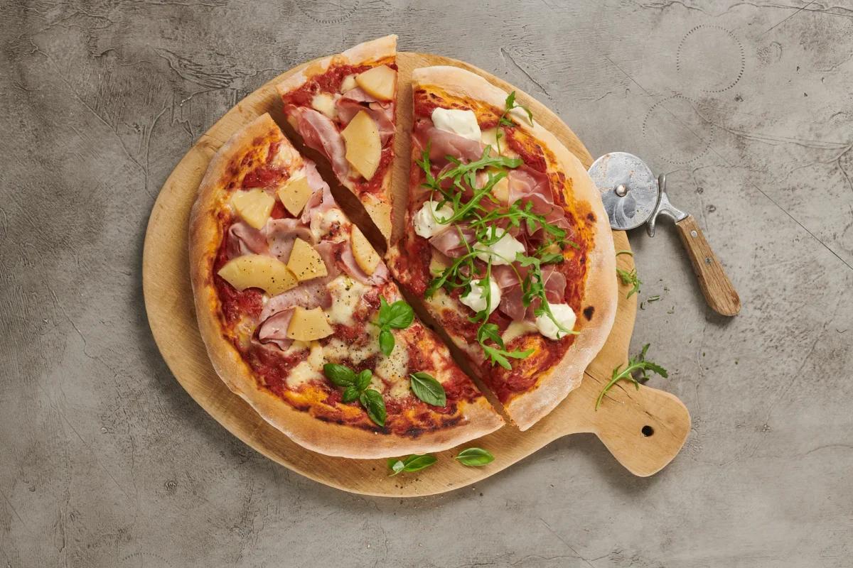 Pizza aus der Kategorie Gebäck salzig. Das fertige Gericht schön angerichtet und fotografiert aus Vogelperspektive (Food Fotografie). Serviervorschlag, Original Tiptopf Rezept, aus dem bekanntesten Kochbuch der Schweiz