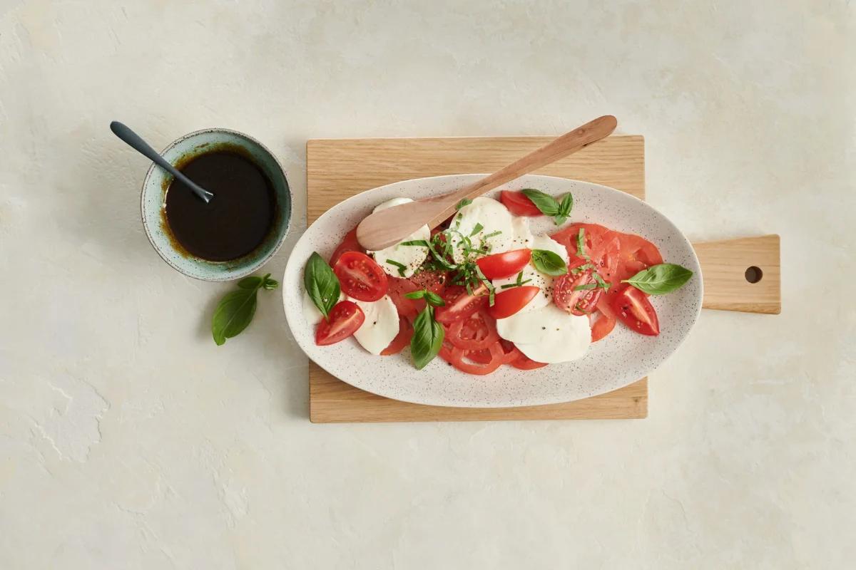 Tomaten-Mozzarella-Salat. Das fertige Gericht schön angerichtet und fotografiert aus Vogelperspektive (Food Fotografie). Serviervorschlag, Original Tiptopf Rezept, aus dem bekanntesten Kochbuch der Schweiz