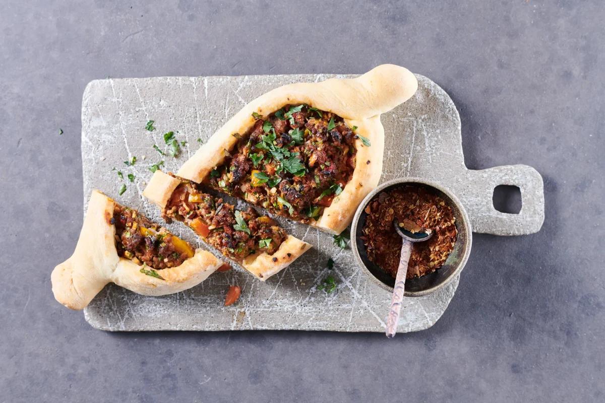 Hackfleisch-Pide. Das fertige Gericht schön angerichtet und fotografiert aus Vogelperspektive (Food Fotografie). Serviervorschlag, Original Tiptopf Rezept, aus dem bekanntesten Kochbuch der Schweiz