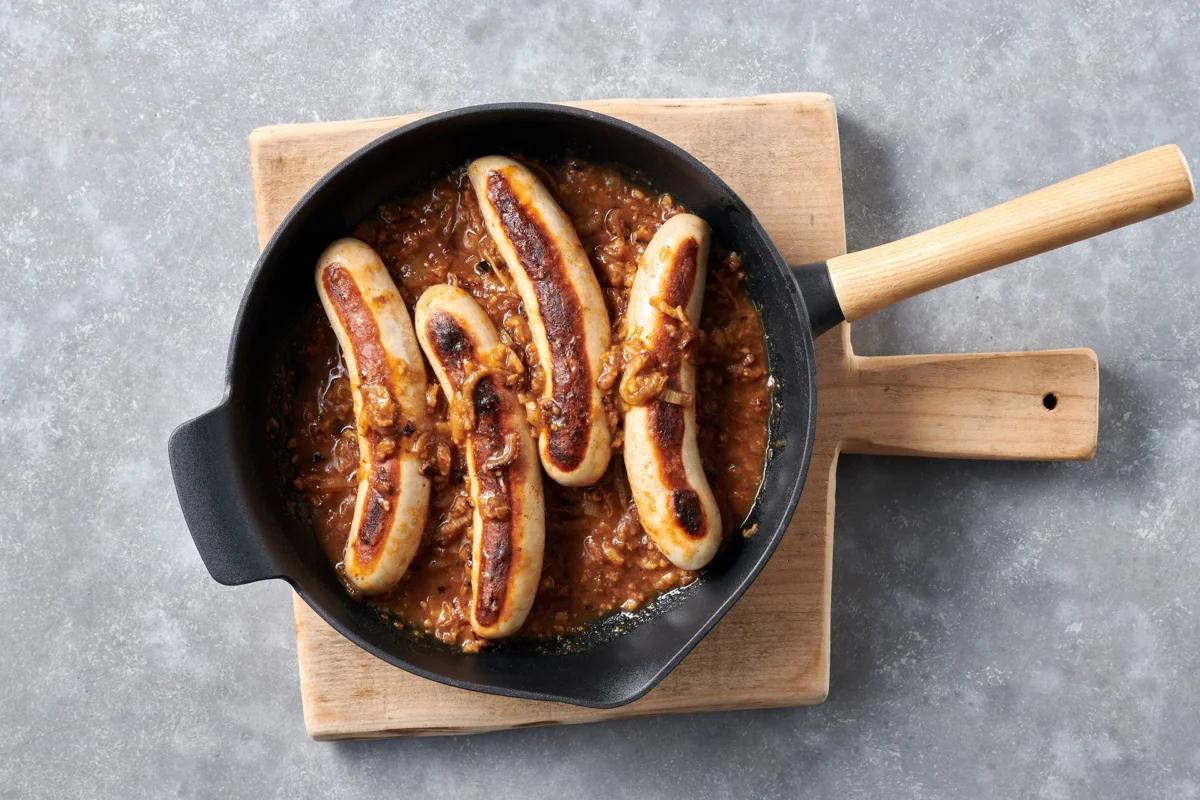 Bratwürste mit Sauce. Das fertige Gericht schön angerichtet und fotografiert aus Vogelperspektive (Food Fotografie). Serviervorschlag, Original Tiptopf Rezept, aus dem bekanntesten Kochbuch der Schweiz