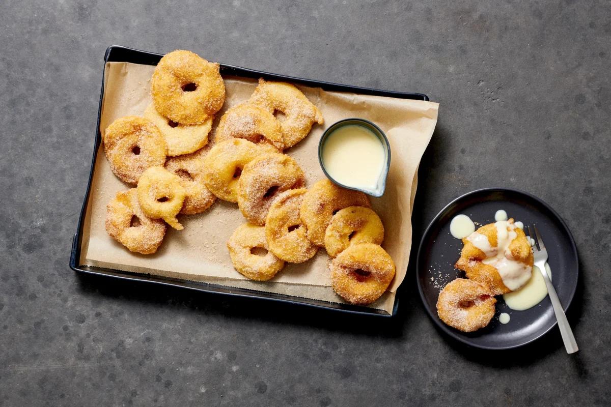 Apfelküchlein aus der Kategorie Desserts. Zubereitungsmethode Frittieren. Das fertige Gericht schön angerichtet und fotografiert aus Vogelperspektive (Food Fotografie). Serviervorschlag, Original Tiptopf Rezept, aus dem bekanntesten Kochbuch der Schweiz