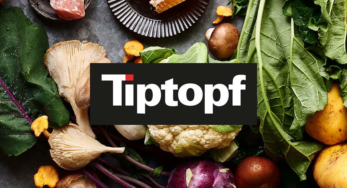 Frisch gewaschenes Gemüse, Kohlblätter, Kartoffeln, Blumenkohl und verschiedene Pilze. Mit Logo „Tiptopf“