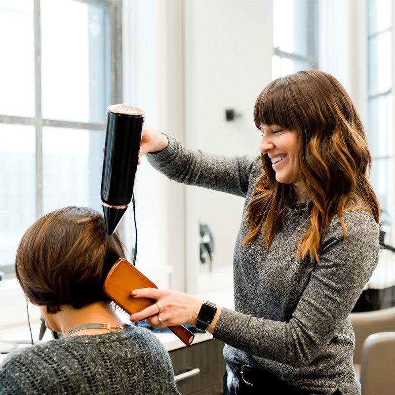 Friseurin bei der Arbeit mit Föhn und Haarbürste
