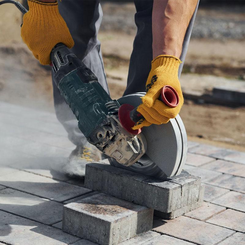 Foto eines Straßenbauers beim Zuschneiden von Pflastersteinen